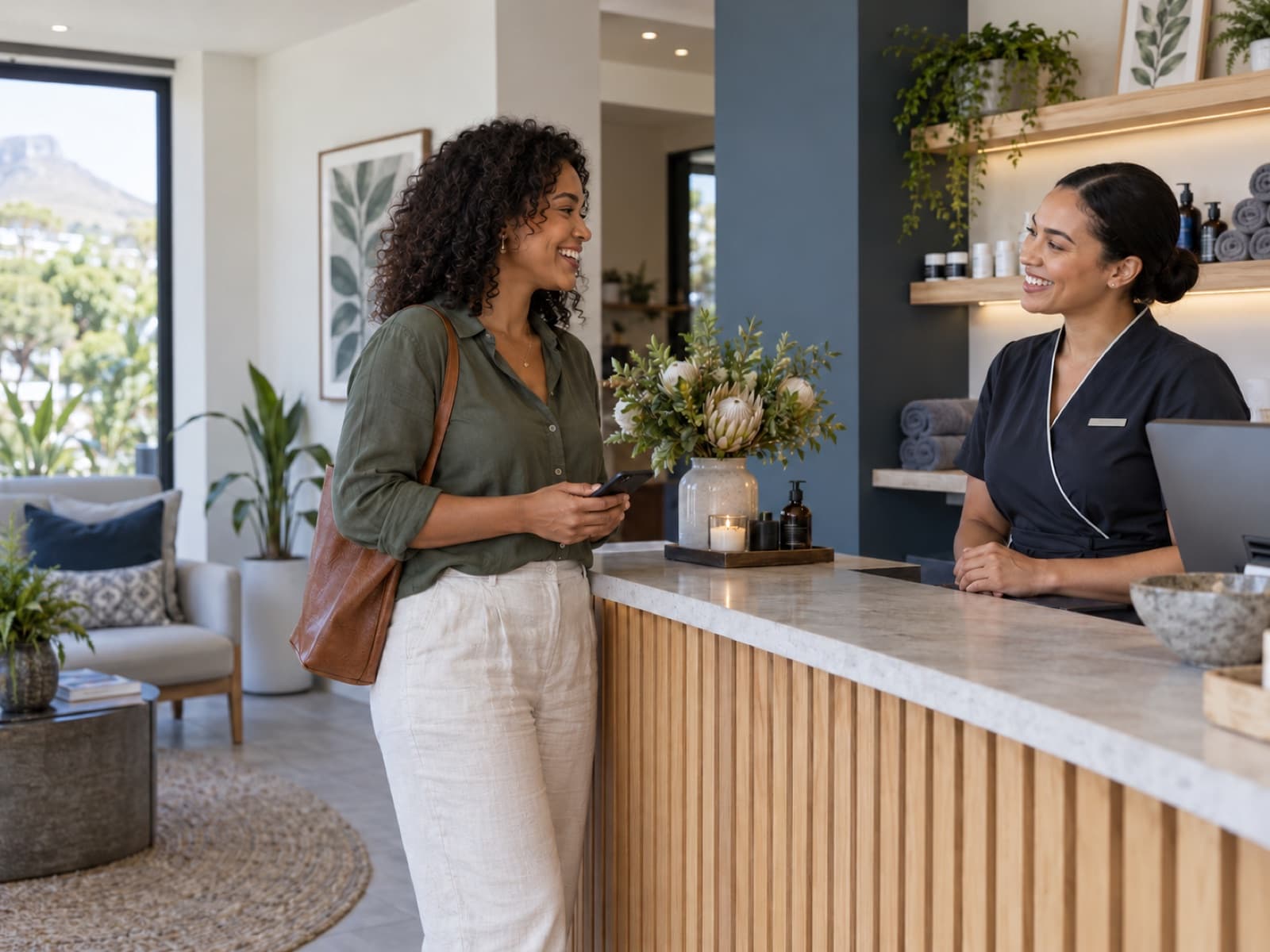 Customer holding a phone while speaking with a staff member at a wellness studio reception.